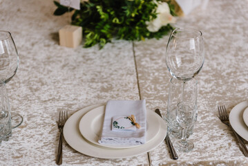 Serving, setting table. Plate decorated linen napkin and silverware cutlery, knife and fork, glasses. Side view. Close up. Wedding set up, dinner table reception. Birthday, baptism and event.