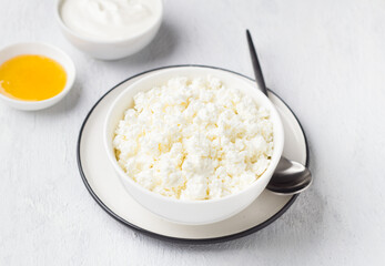 Fresh homemade cottage cheese with honey and sour cream on a light gray background
