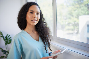 Portrait of beautiful young medical professional looking out of hospital window