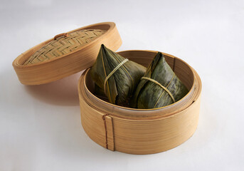 Zongzi - Rice dumpling in bamboo leaves wrapping arranged in a woven rattan basket isoalted on white background. Concept of Dragon Boat Festival traditional food.