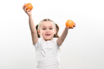 Portrait of a small beautiful girl on a white background with tangerines in her hands.