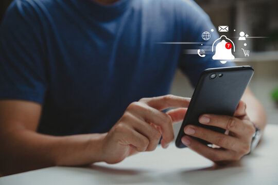 Hand of young business using smartphone with bell ringing and icons for application notification alert concept.