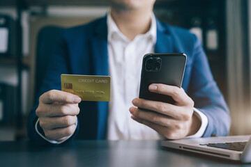 Male businessman use credit cards to conduct financial transactions through phones.