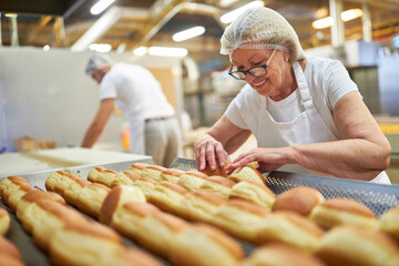 Elderly woman as a baker baking donuts