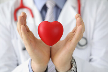 Doctor cardiologist holds red heart in air