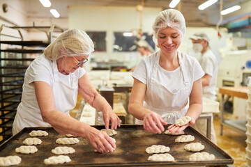  Baker apprentice with a colleague baking yeast plaited bread