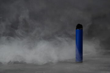 Blue electronic cigarette vape on dark background with smoke.