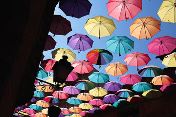 Fototapeta na wymiar Umbrellas Suspended and Joined with Each other in the Street to Form a Roof of Colorful Umbrellas