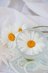 Obraz na płótnie Canvas Chamomile flowers in a glass vase with pearls