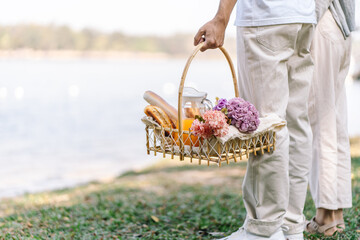 Fototapeta na wymiar Couple walking in garden with picnic basket. in love couple is enjoying picnic time in park outdoors
