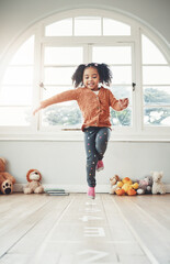 Hopscotch, happy and girl play in home having fun, enjoying games and relax in bedroom. Childhood, kindergarten and excited child balance for jumping game, playing and entertainment activity on floor