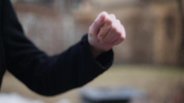 Close-up hand of nervous man sqeezing paper cup outdoors. Unrecognizable stressed Caucasian guy throwing away coffee in urban city. Lifestyle and nervousness concept
