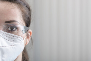 Nurse's close-up half face protrait with protective glasses and N95 mask