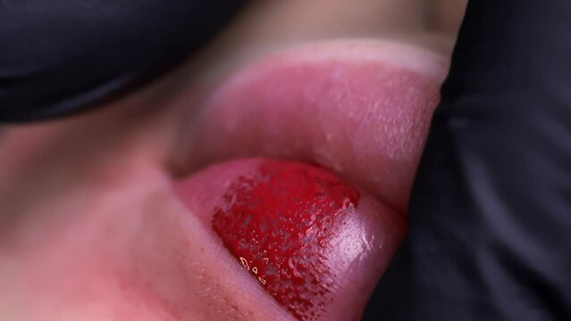 Macro-shooting of the permanent lip makeup procedure master makes punctures with a machine applying lip pigment. High quality 4k footage