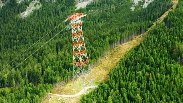 Power line pylon high in the mountains surrounded by trees, aerial view