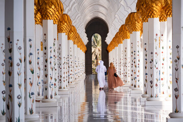 Two people in arab clothes walking in Sheikh Zayed Grand Mosque in Abu Dhabi, UAE