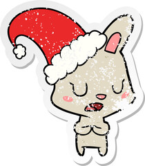 distressed sticker of a cartoon rabbit wearing christmas hat