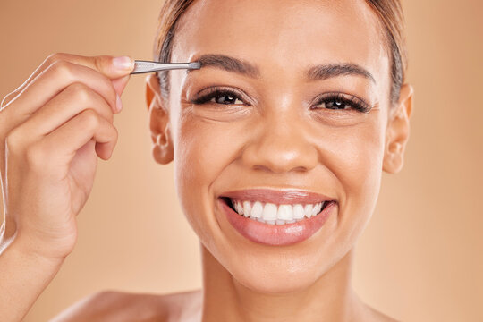 Woman, face and tweezer on eyebrow for skincare beauty, grooming or trimming against a studio background. Portrait of happy female tweezing eyebrows with big smile for facial cleaning or hair removal