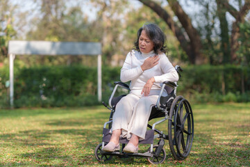 Asian elderly woman in wheelchair suffering from heart disease at the park.