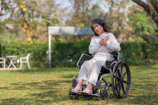 Asian elderly woman in wheelchair suffering from heart disease at the park.