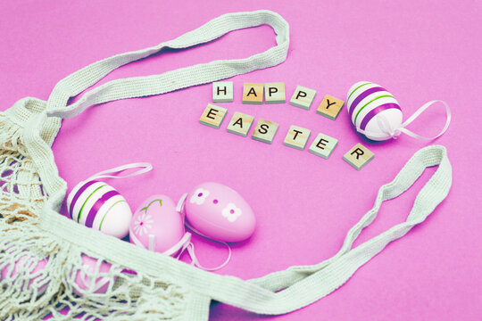 Happy easter with colorful painted eggs and cotton string bag on pink background