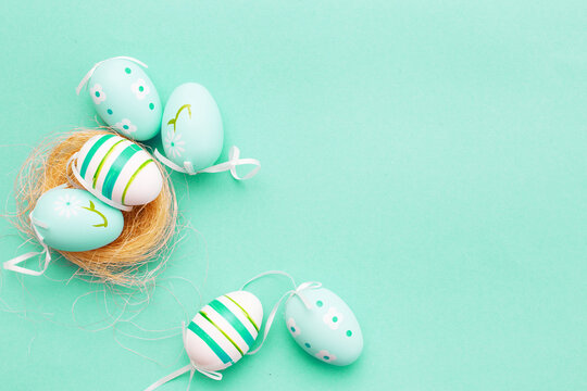 colorful handmade painted eggs in the nest on green background