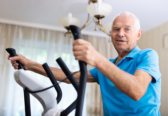 Fit senior man at home doing cardio work out on an elliptical machine
