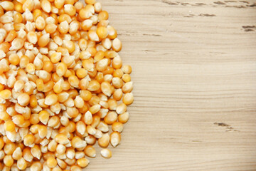 Small grains of yellow dried corn on a brown wooden background