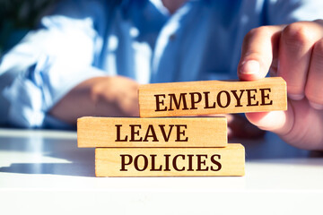 Close up on businessman holding a wooden block with "Employee Leave Policies" message