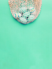 easter colorful painted eggs in the cotton string bag on green background. banner