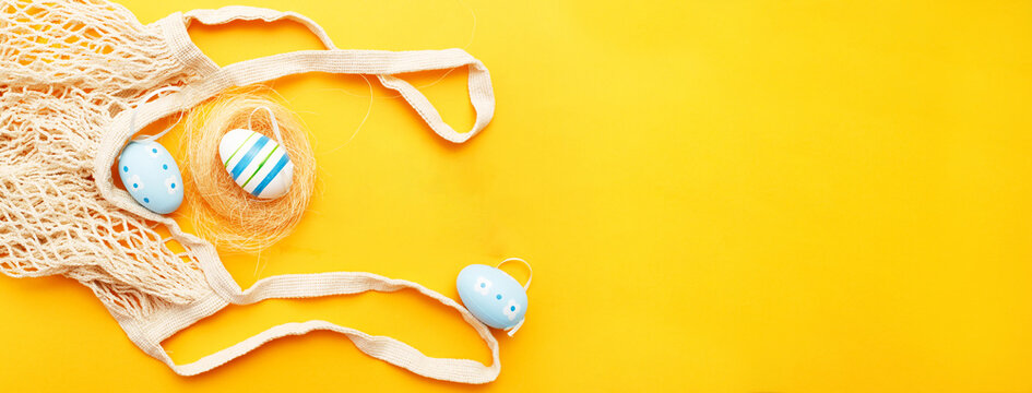 happy easter with colorful painted eggs and cotton string bag on orange background