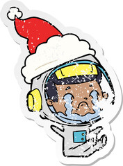 distressed sticker cartoon of a crying astronaut wearing santa hat