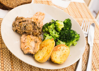 fried river trout fillet with a complex side dish of broccoli, baked potatoes and mushroom sauce