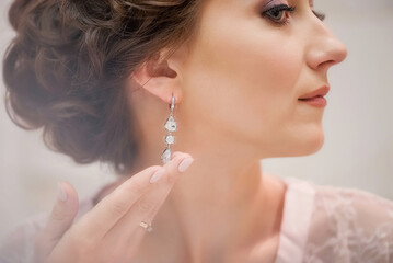 Wedding day. Bride morning. Makeup for the bride. Wedding make-up. Bride portrait. Beautiful young girl. Portrait. Married Wedding. Professional makeup. Bride in a diadem. Girl puts on earrings