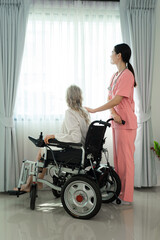 Nurse standing beside senior woman and holding hands to encourage woman to cure from disease in living room,Medical care for the senior at home concept.