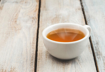 A cup of fragrant hot tea on a light background. Herb tea. Hot drink. White cup with tea.