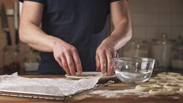 Home baking - making fresh Greek bagels or koulouri of Thessaloniki. Coating in sesame seeds.