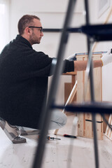 Man assembling new wooden shelf and furniture in the apartment.