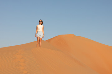 Beautiful young woman posing on the dunes in the desert.