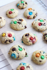 Stack of children's homemade cookies with colorful chocolate candies in a sugar glaze on a white light background. Selective focus. High quality photo