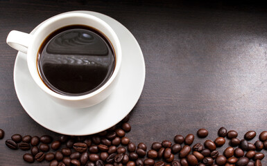 Hot Coffee cup and coffee beans roating on the wooden table