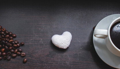 Obraz premium Coffee cup, heart shaped white yarnon on wooden surface