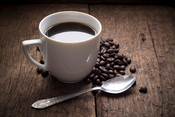 Hot Coffee cup and coffee beans roating on the wooden table