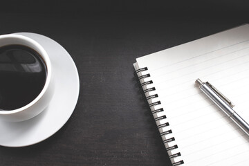 Cup of coffee and blank notebook on the wood