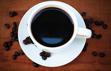 Hot Coffee cup and coffee beans roating on the wooden table