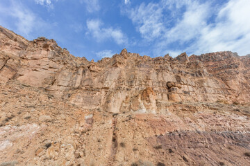 Obraz premium Looking up at a rocky cliff face with blue sky