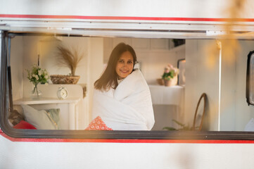 Portrait of a caucasian woman looking out of a trailer window. Travel in a camper in autumn. 