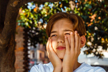 Teenage boy doing italian hand gestures while standing under a tree