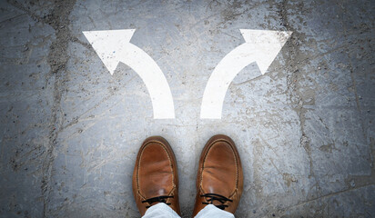 Brown leather shoes and two right and left chalky arrows on asphalt - choice concept
