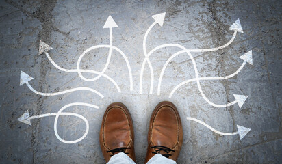 Brown leather shoes and many winding chalky arrows on asphalt - decision concept